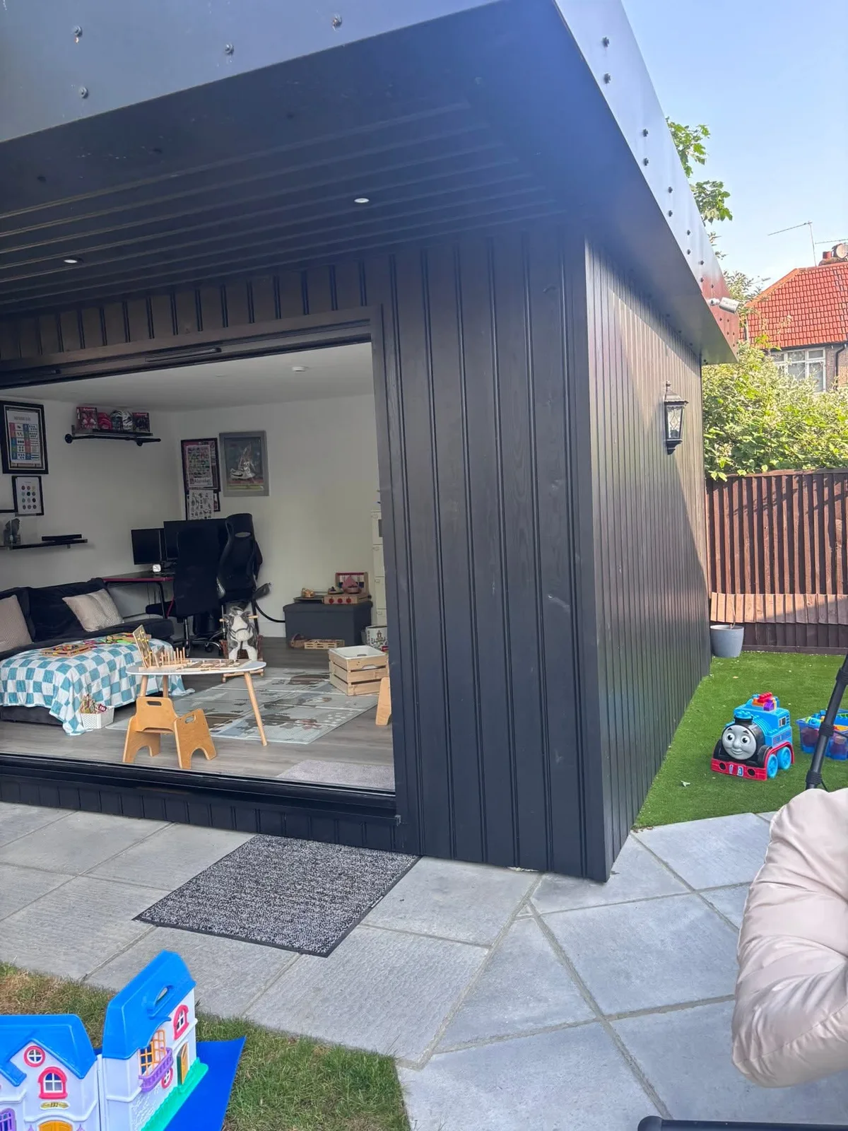 The purpose-built garden outbuilding under a tree, with bi-fold doors looking onto a calm interior