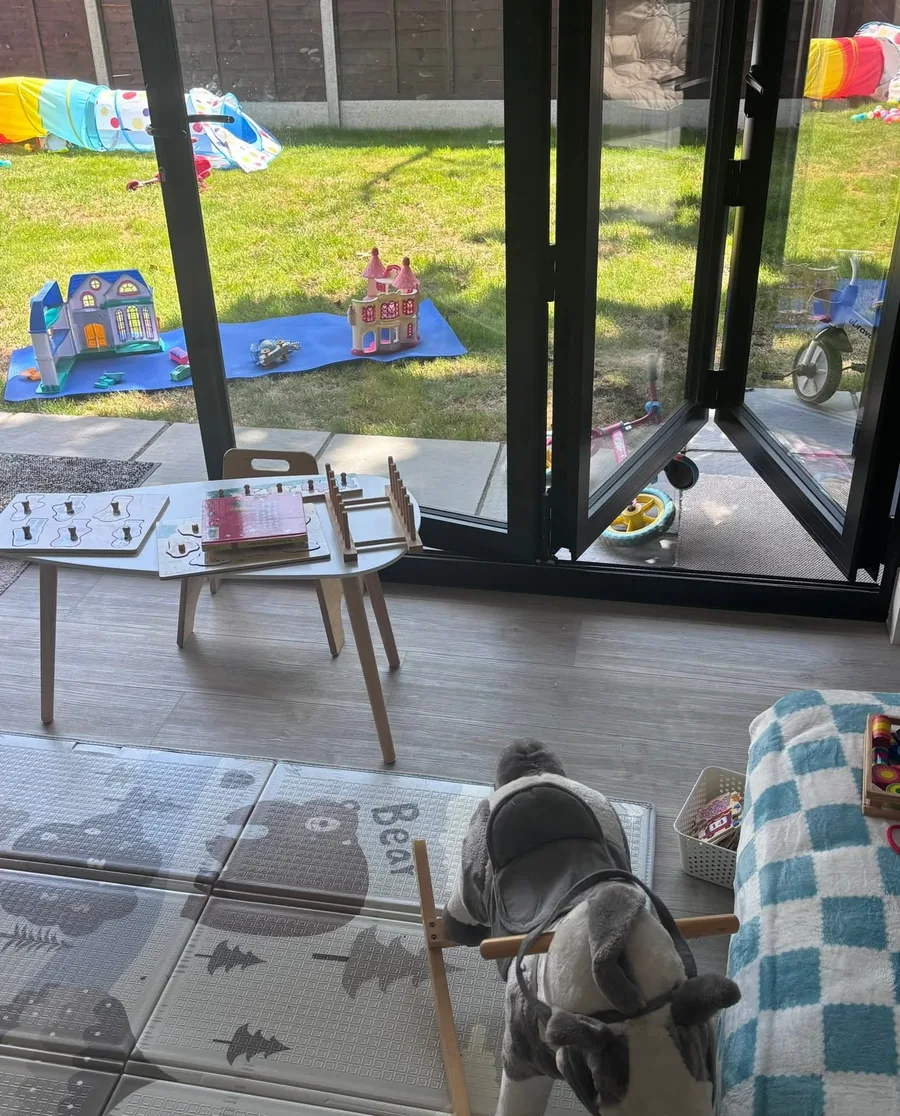 Looking through the bi-fold doors onto the garden, with playhouses on the lawn