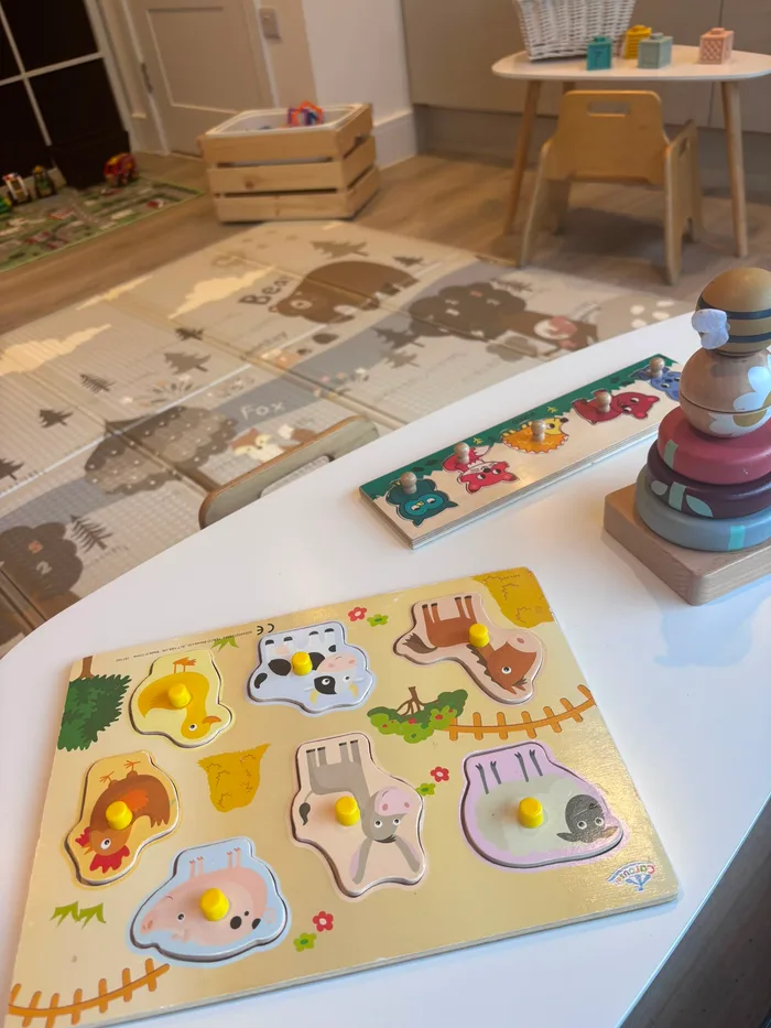 A wooden farm-animal puzzle and stacking toy on the play table