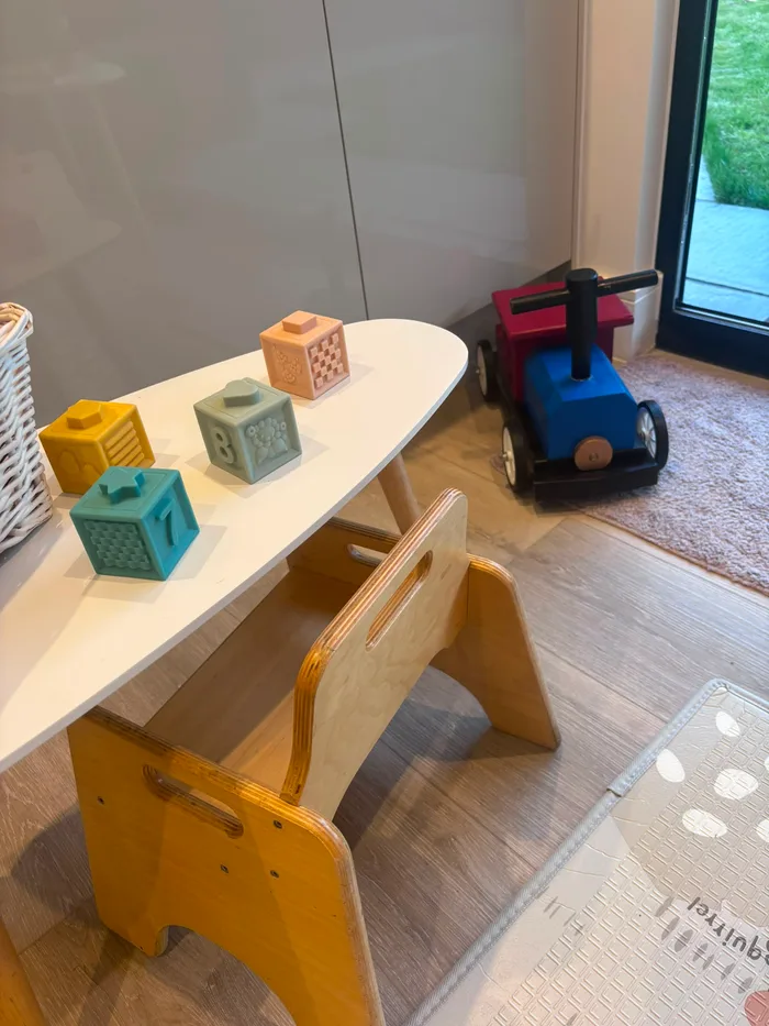 Soft sensory number cubes on the play table, with a ride-on toy by the door